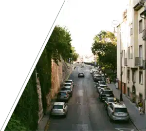 A hilly street lined with buildings and cars.