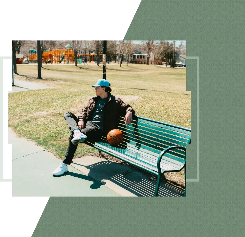 A man with a basketball sits on a park bench