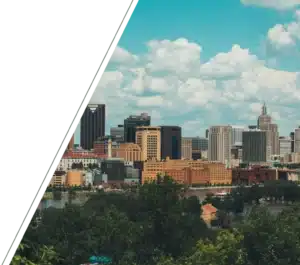 A skyline of buildings overlooks a river and trees