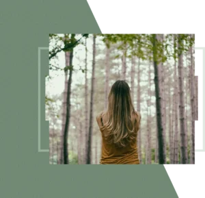 A woman stands with her back to the camera in a forest