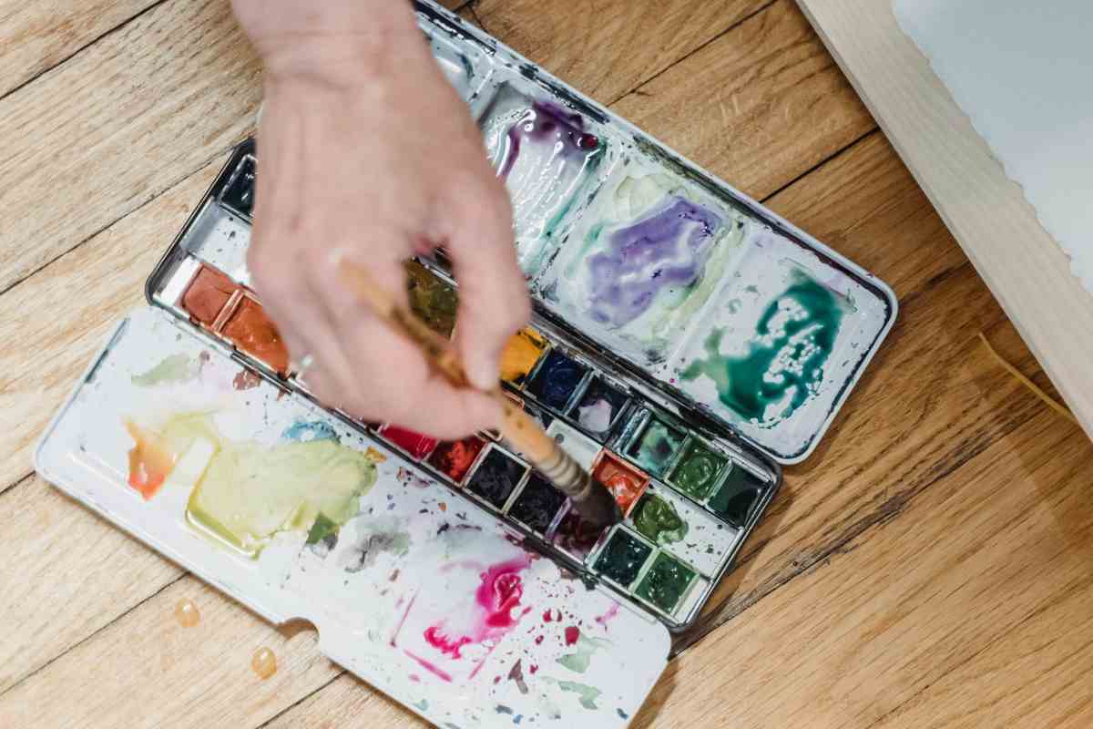 Hand using watercolor paint palette, symbolizing creativity and emotional expression