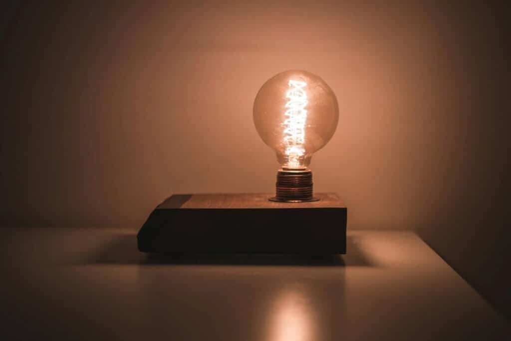 Glowing light bulb on wooden base, representing inspiration and creative ideas