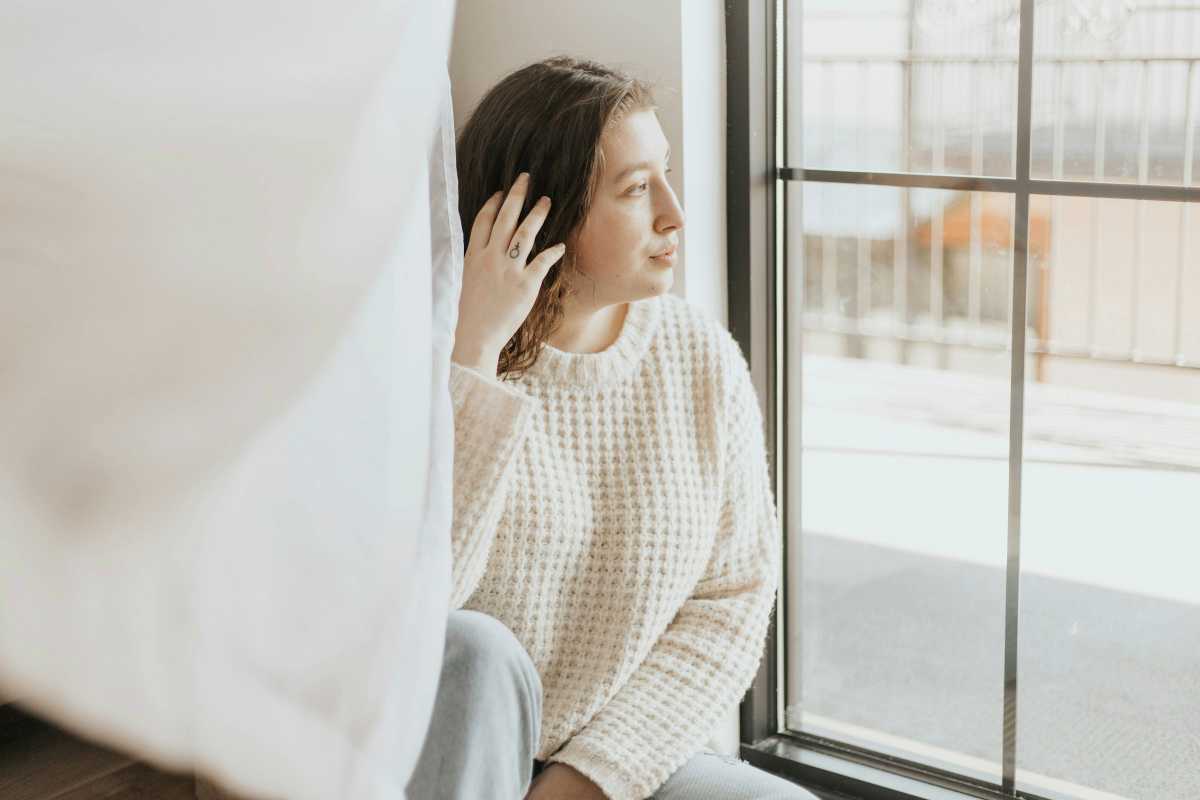 Person sitting by a window, quietly reflecting before a therapy session.