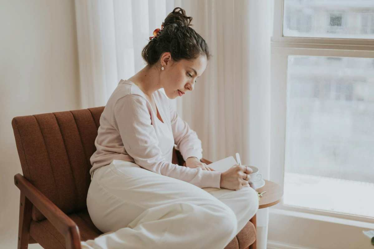 Woman journaling in a notebook as a therapeutic way to process grief and emotions.