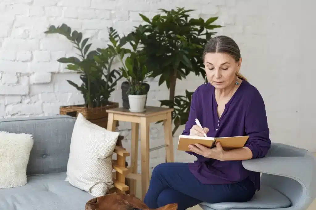 serious attractive female writing down on notebook