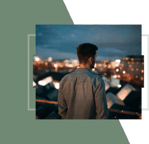 Man in a denim shirt viewing city lights at night.