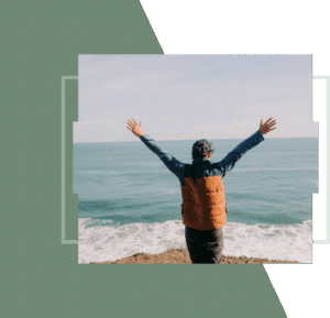 Man with raised arms looking at the ocean.