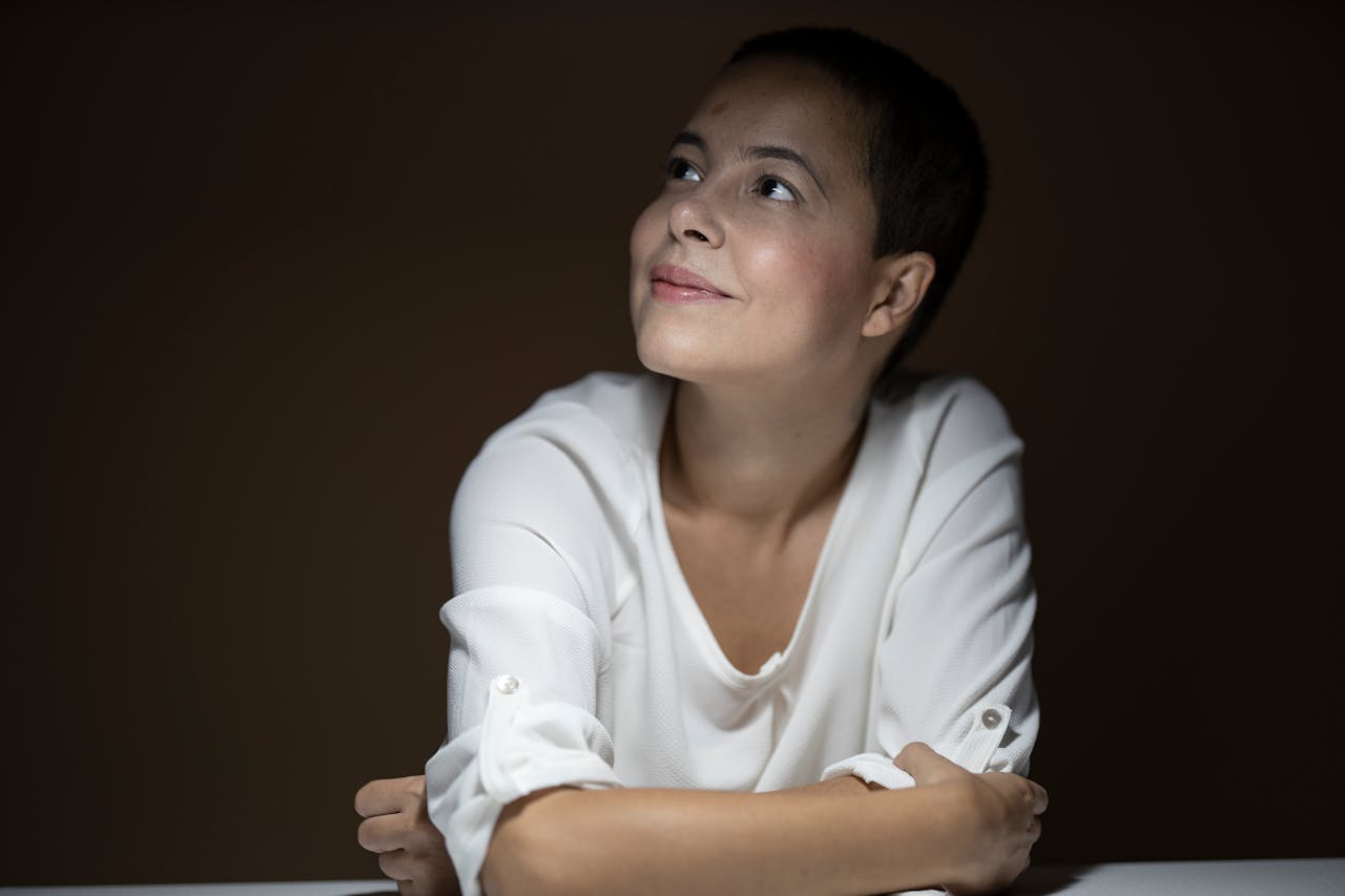 Person sitting thoughtfully and looking upward, representing self-reflection and emotional awareness when considering therapy