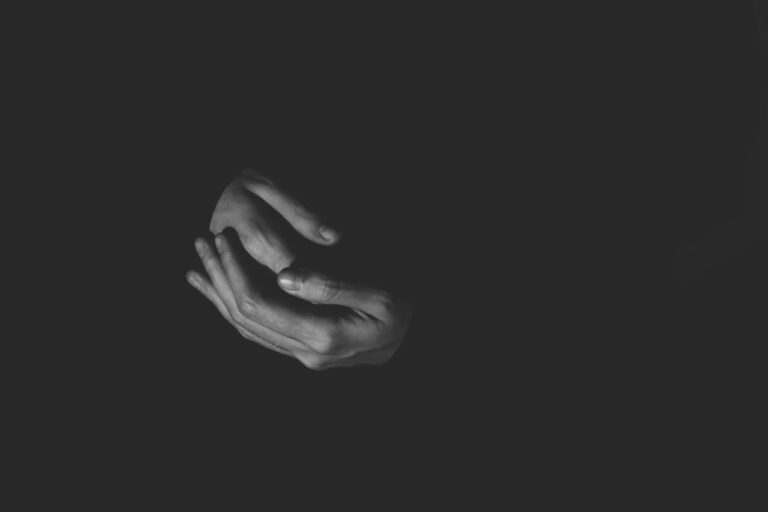 Hands gently held together in darkness, symbolizing emotional awareness and managing anger issues calmly.