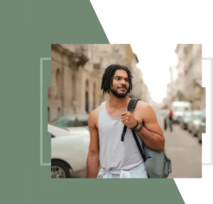 A man carrying a bag is walking down a busy street with cars and tall buildings in the background