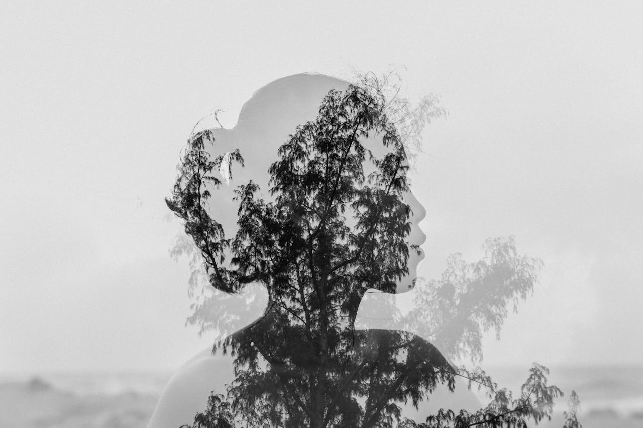 Double exposure silhouette of a woman's head with trees symbolizing overlapping thought patterns in ADHD and anxiety