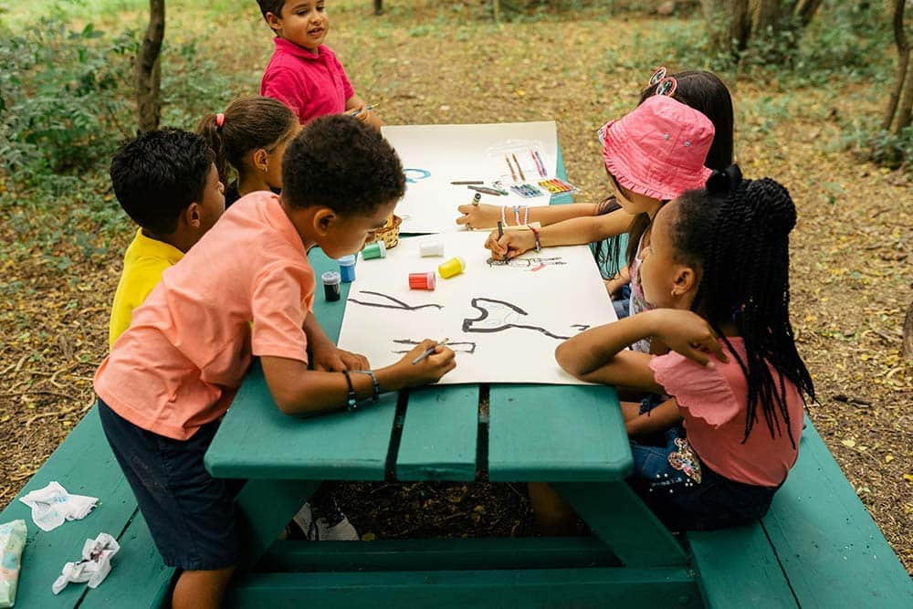A group of children sitting at a picnic table.