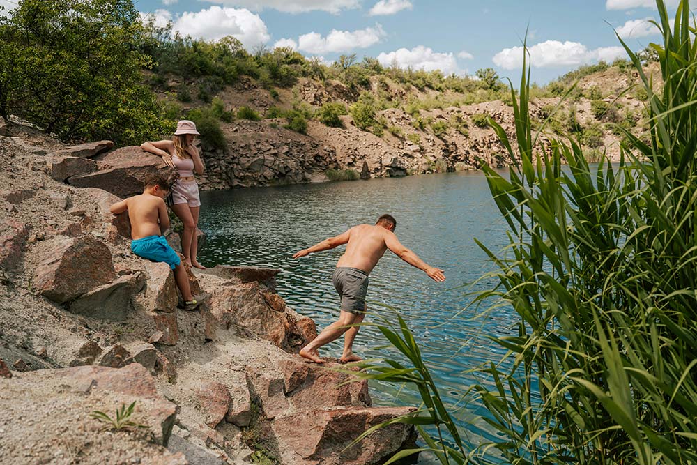 Young people jumping from rocks into a quarry lake