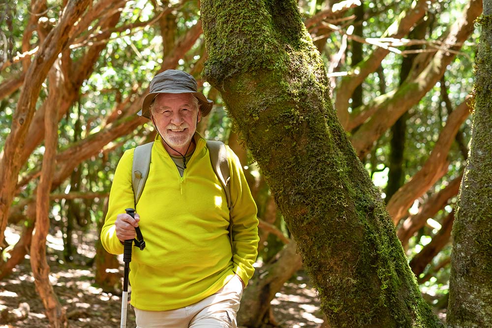A happy senior man wearing a backpack and smiling.